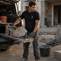 Contractor handling a tile saw while wearing the black Falco + Petra Torch Shirt
